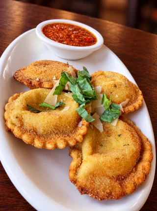 Four golden fried cheese ravioli with basil, shaved parmesan and a ramekin of marinara.