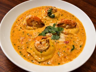 Lobster ravioli topped with shrimp, basil and parmesan in pink sauce.